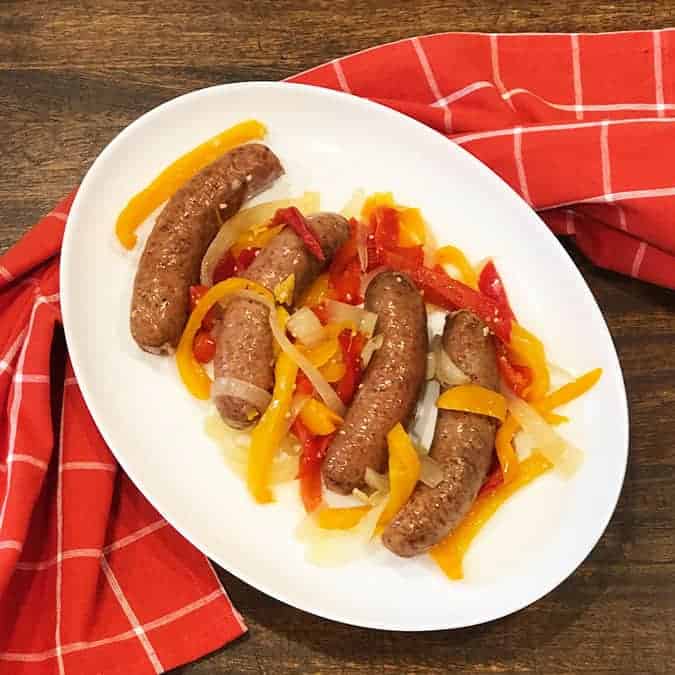 Crockpot Sausage and Peppers on a white plate with a red linen.
