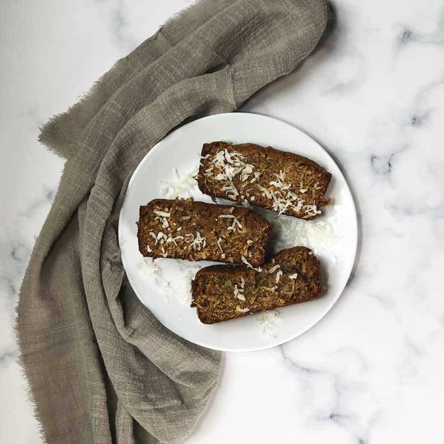 Coconut Pudding Banana Bread slices on a white plate with a gray linen