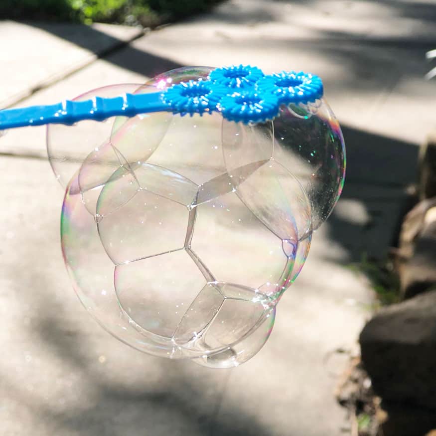 Unbreakable bubbles hanging from a blue bubble wand. 