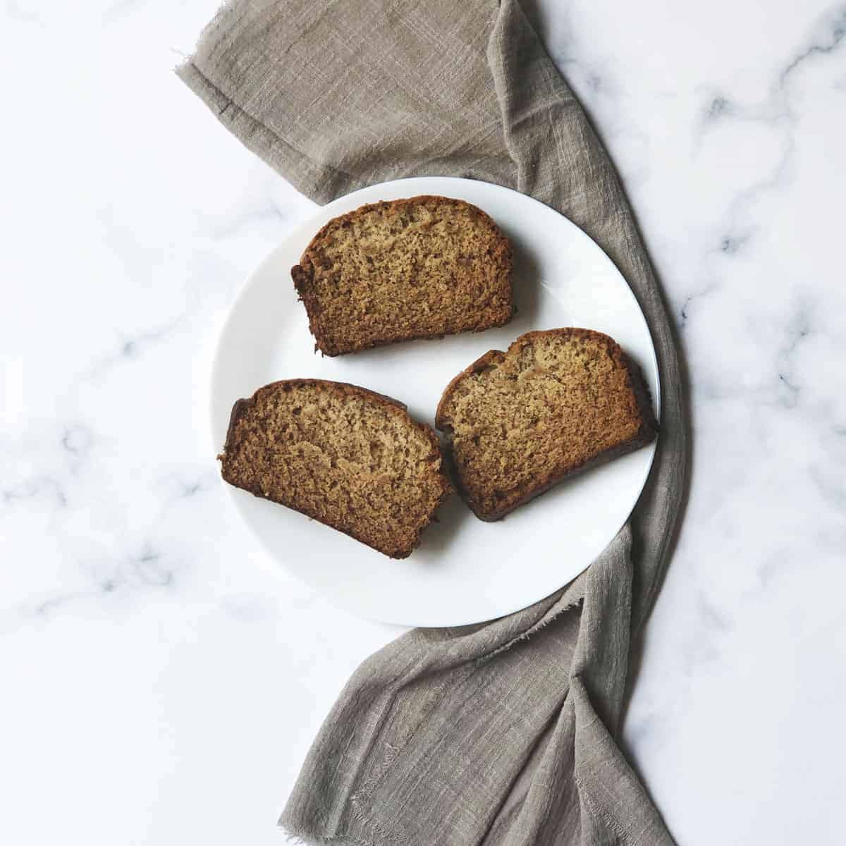 Copycat Starbucks banana bread slices on a white plate with a gray linen. 