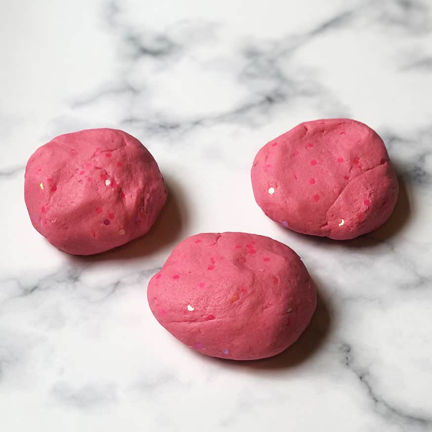 Pink glitter play dough on a marble background. 