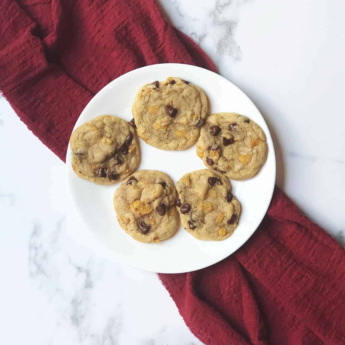 Corn Flake Chocolate Chip Cookies on a white plate with a red linen under it