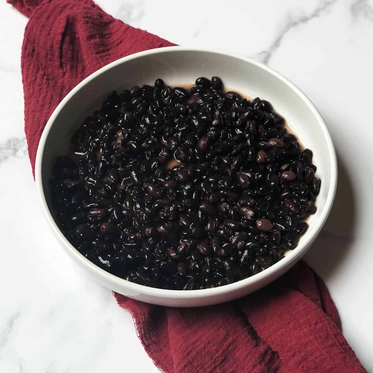 black beans in a white bowl with a red linen