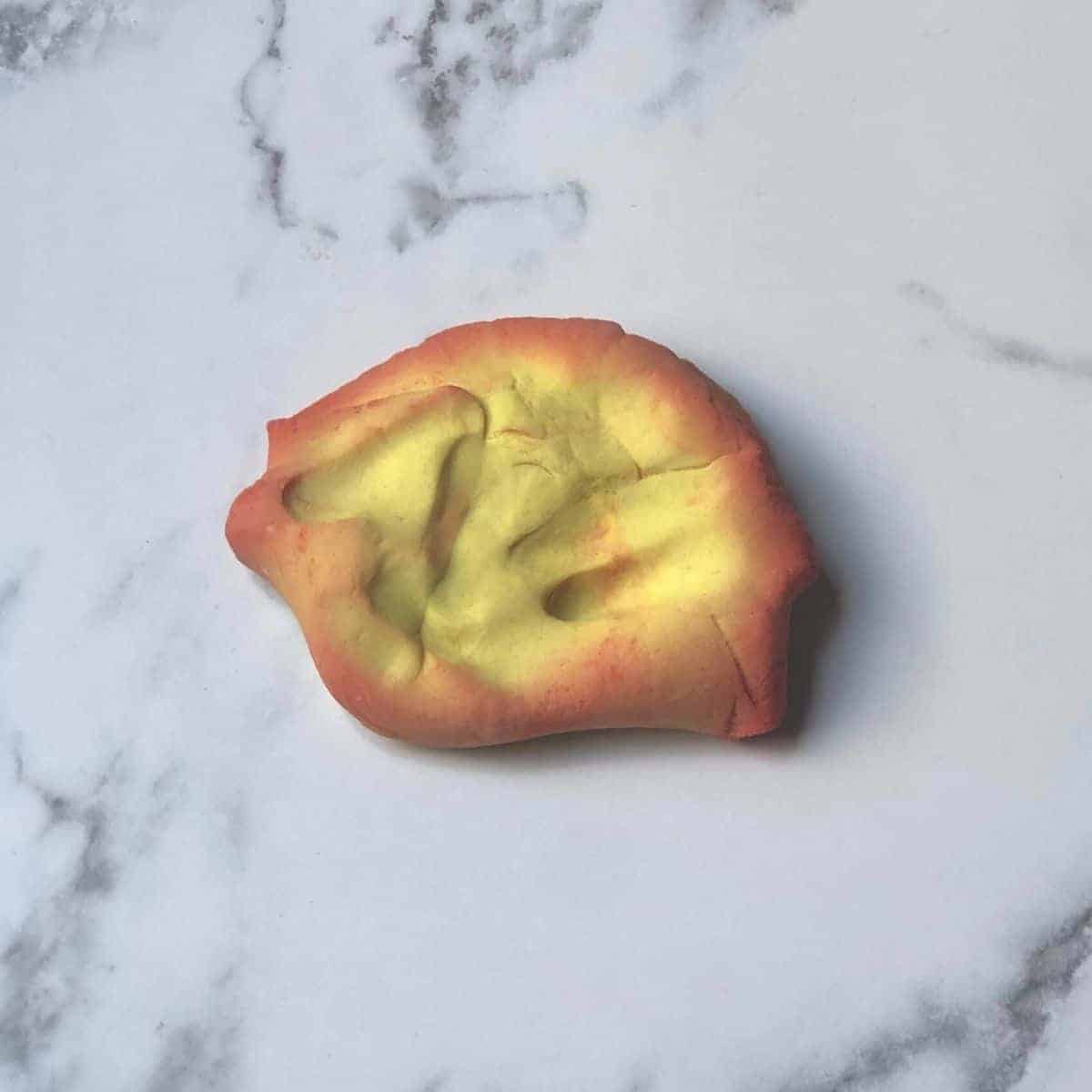 color changing play dough on a marble background. The play dough is both yellow and red. 