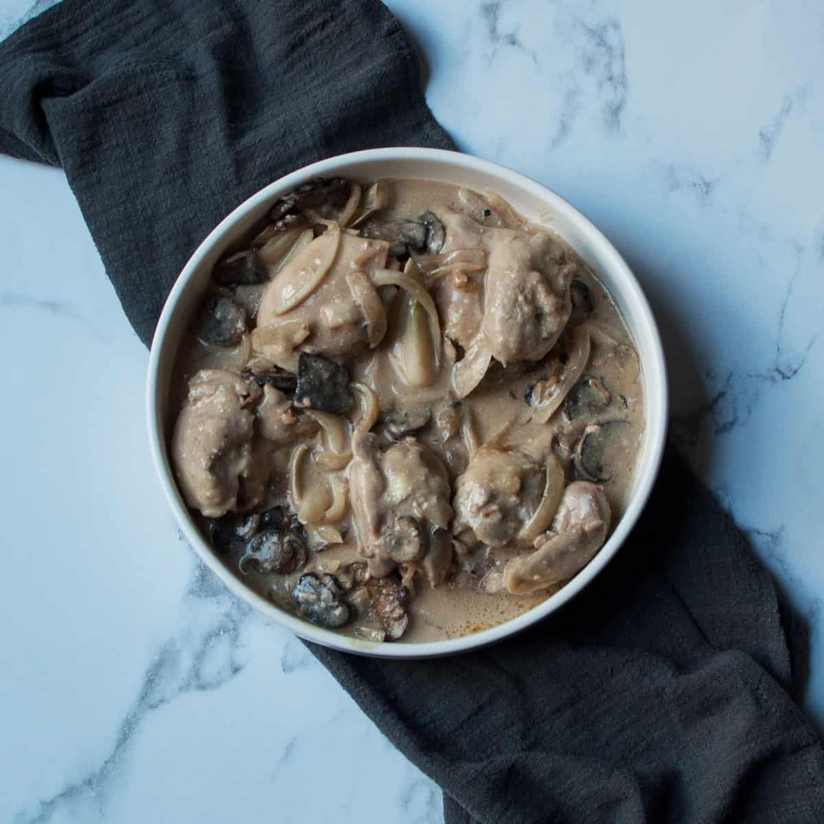 Crockpot Chicken with Onion Soup Mix in a white dish with a gray napkin