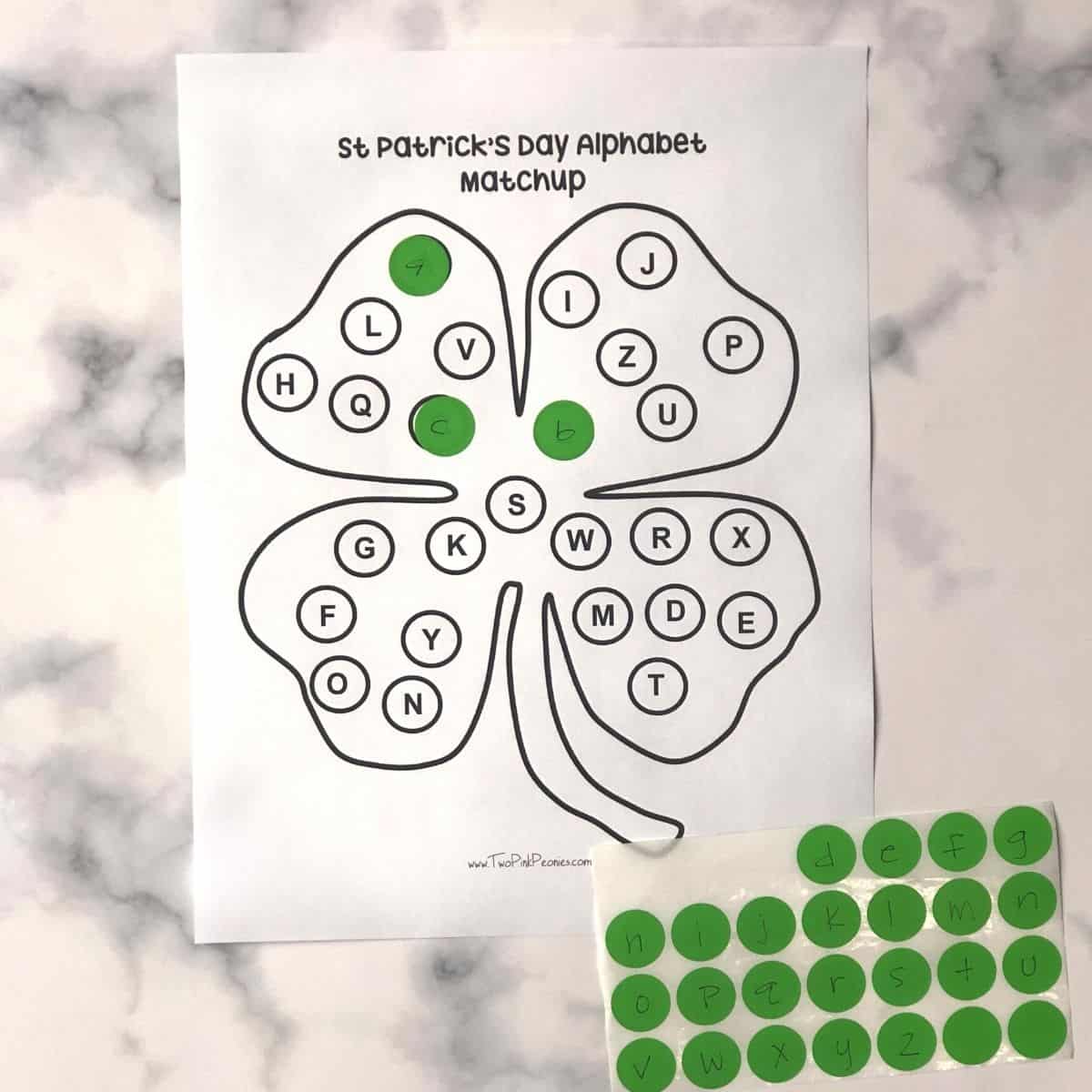 a worksheet that has a four leaf clover on it. There are alphabet dots on it and then dot stickers with letters written on it. 