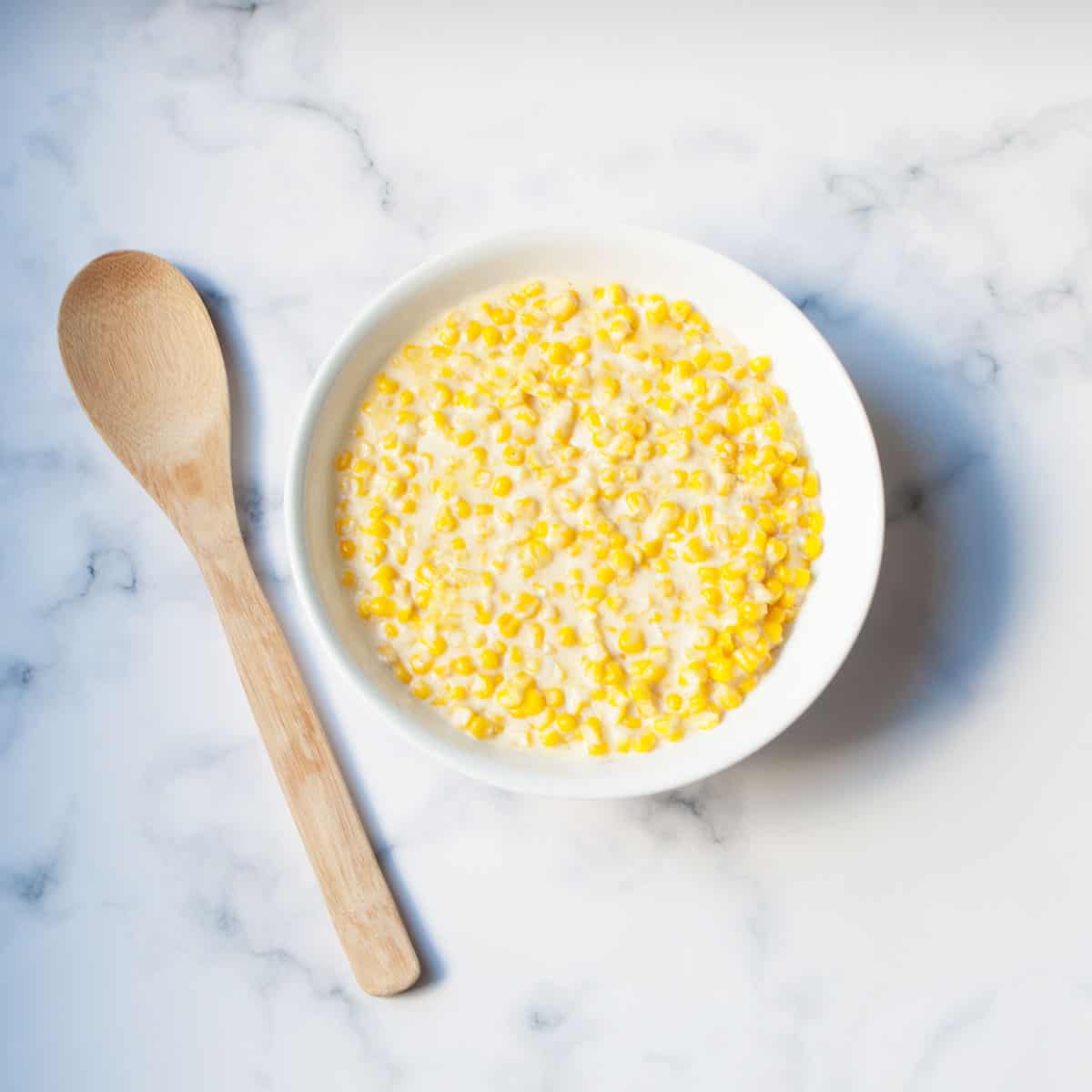 bowl of instant pot creamed corn there is a spoon next to it