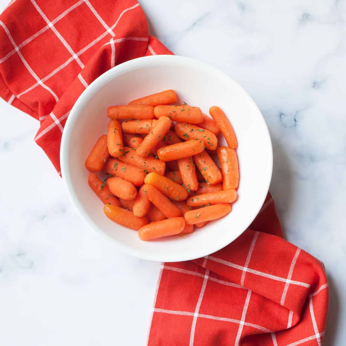 Instant Pot Maple Carrots in a white bowl with a red linen